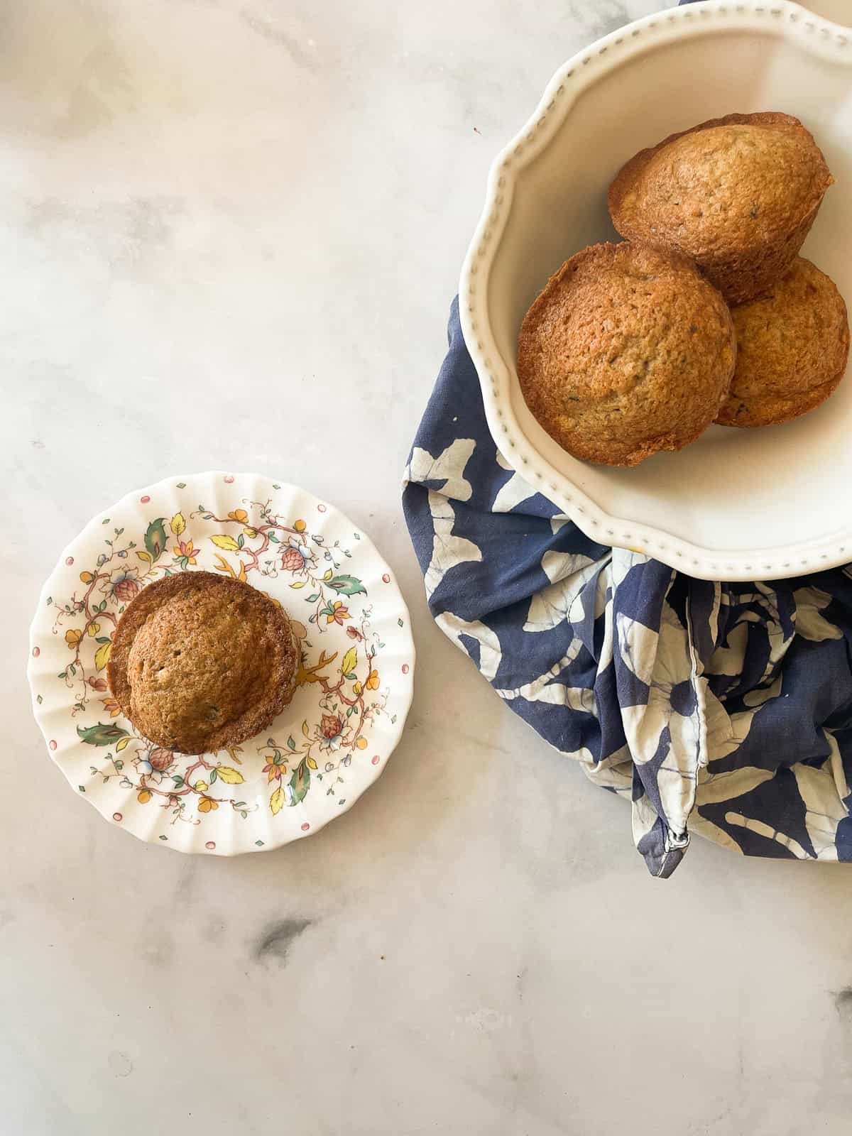 A banan muffin on a plate next to a bowl of muffins.