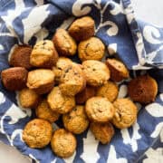 A bowl lined with a napkin full of banana mini muffins.