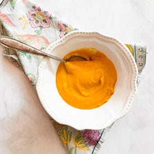 A spoon rests in a bowl of butternut squash soup.