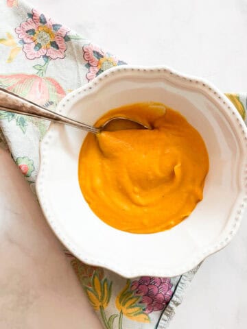 A spoon rests in a bowl of butternut squash soup.