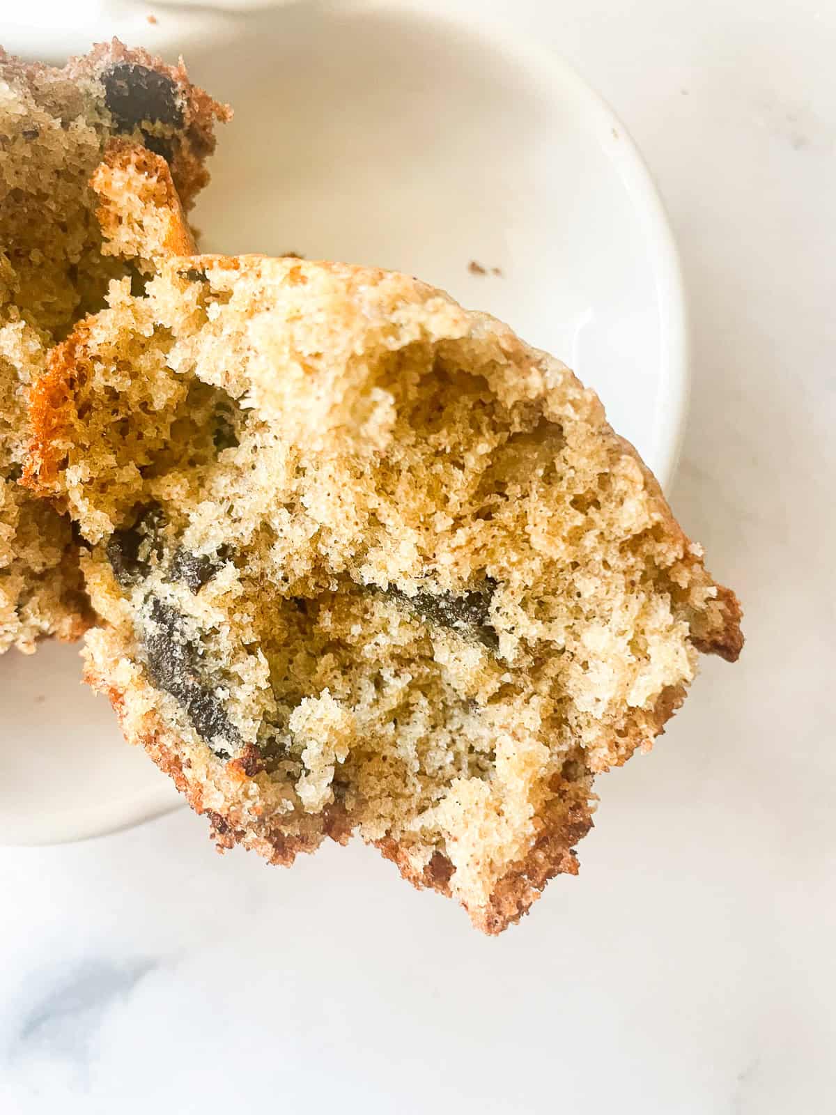 Chocolate peeks out of a chocolate chunk banana muffin.