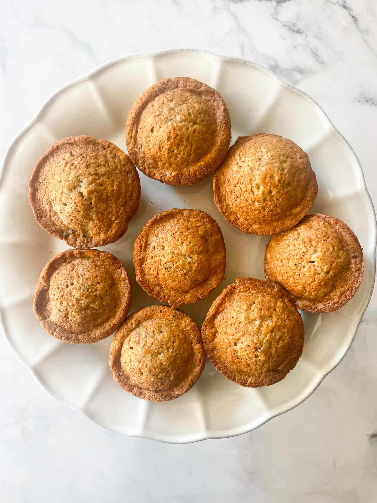 Gluten free chocolate chunk banana muffins on a cake plate.