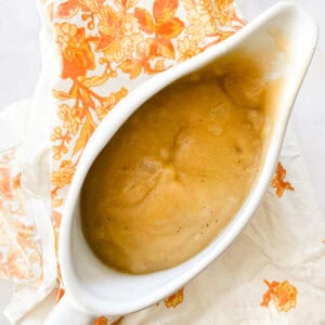 A pitcher of gluten free gravy on a napkin.