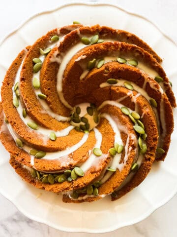 A gluten free pumpkin bundt cake topped with maple glaze and pumpkin seeds.