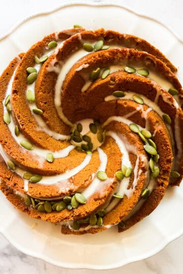 A gluten free pumpkin bundt cake topped with maple glaze and pumpkin seeds.
