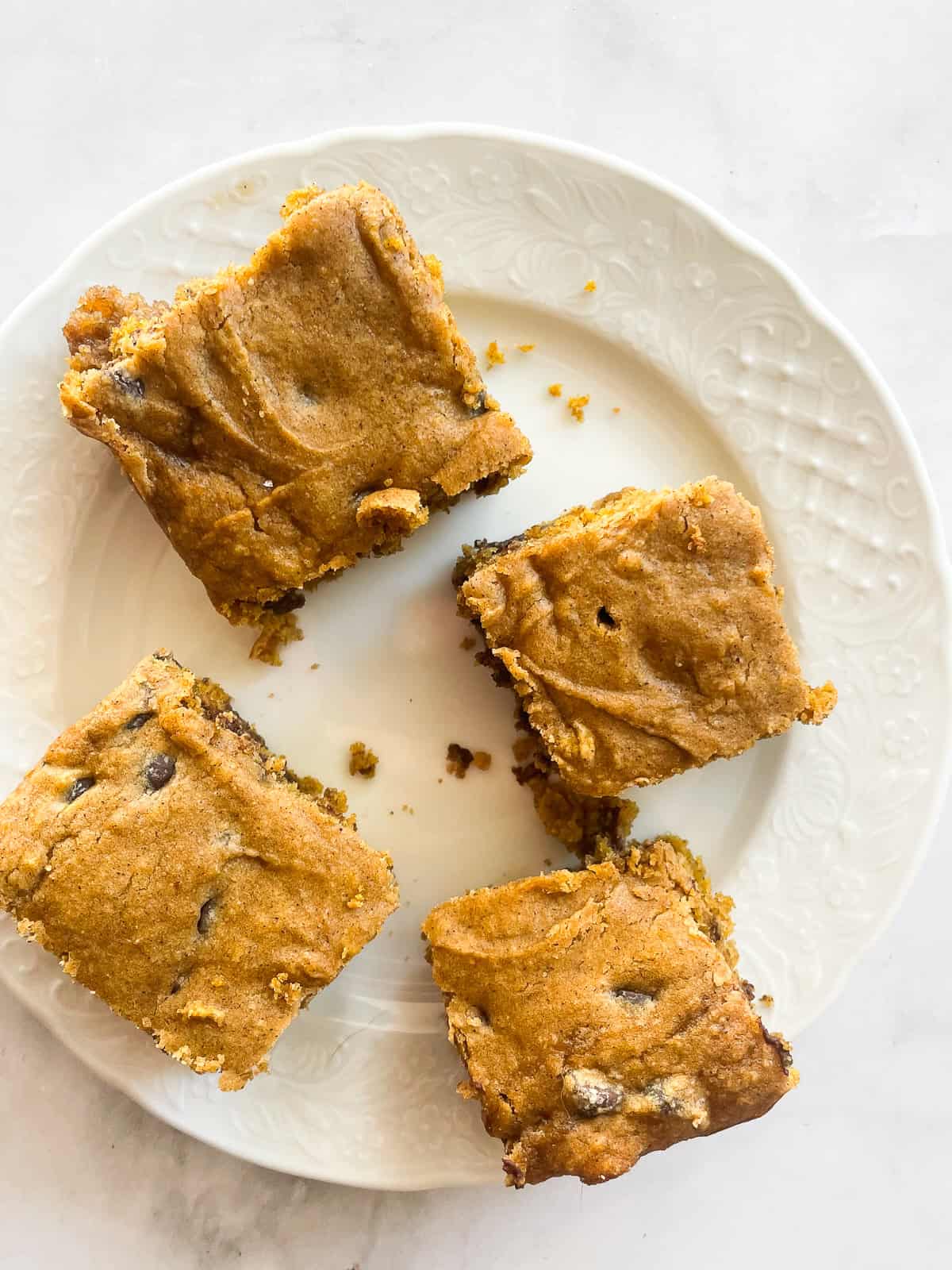 Four pieces of pumpkin chocolate chip cake on a white plate.