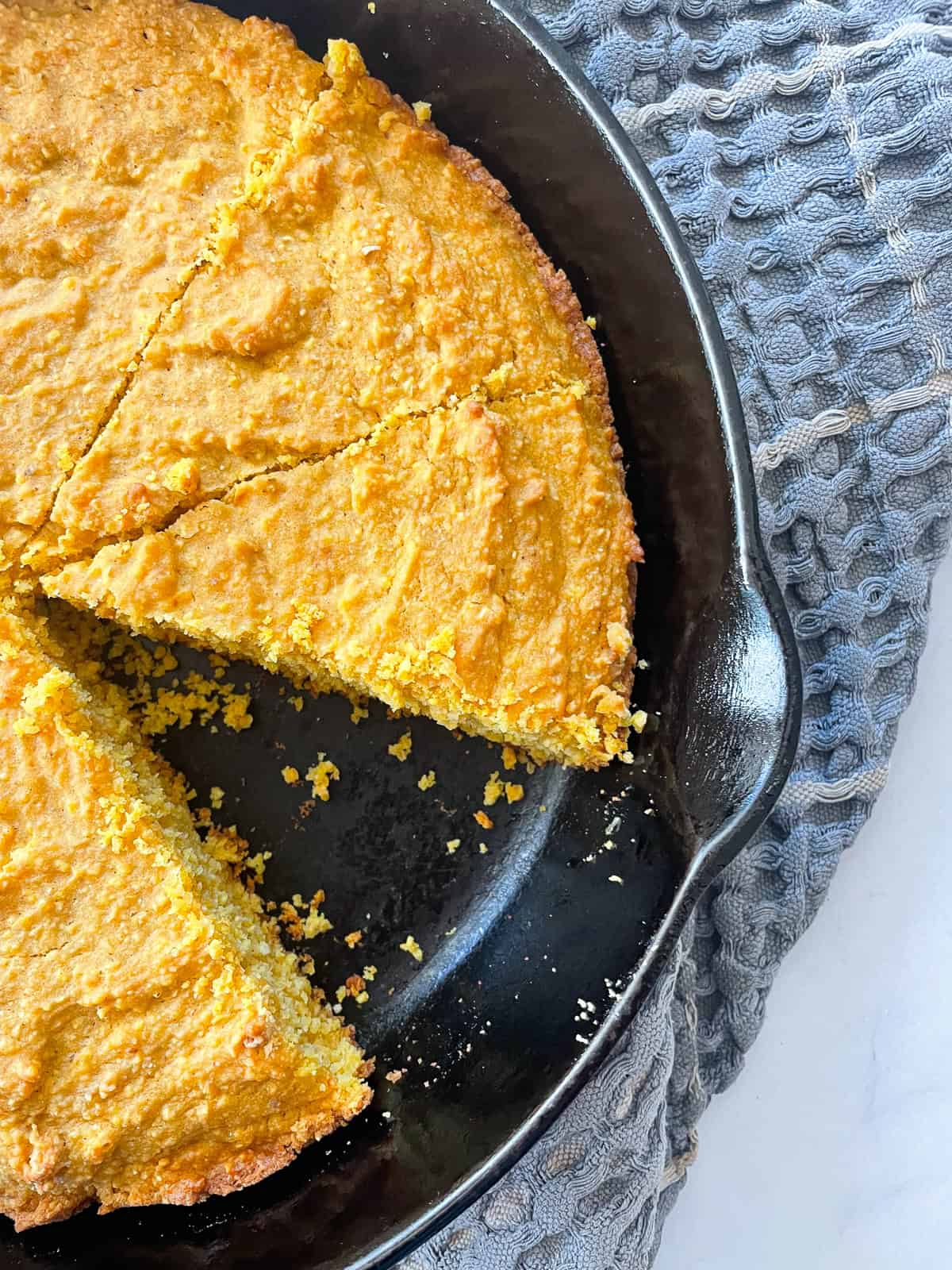 A slice cut out of a pan of pumpkin cornbread.