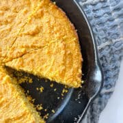 A slice cut out of a pan of pumpkin cornbread.