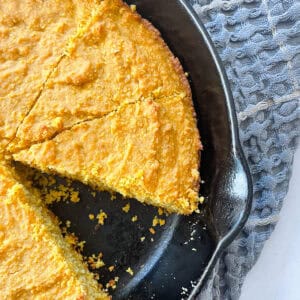 A slice cut out of a pan of pumpkin cornbread.