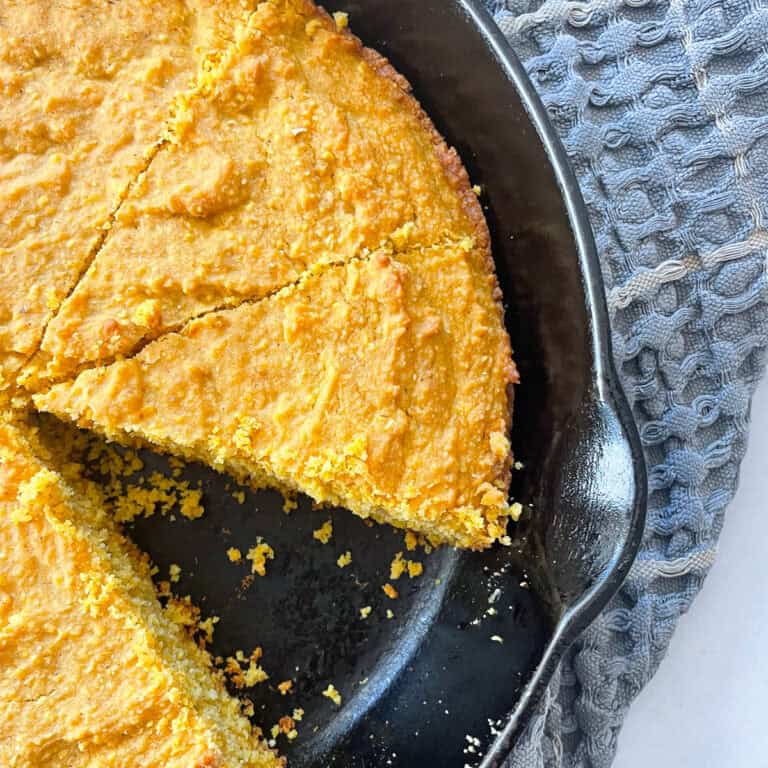 A slice cut out of a pan of pumpkin cornbread.
