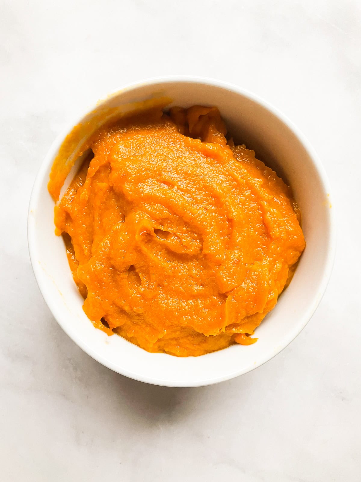 A white bowl of homemade pumpkin puree.