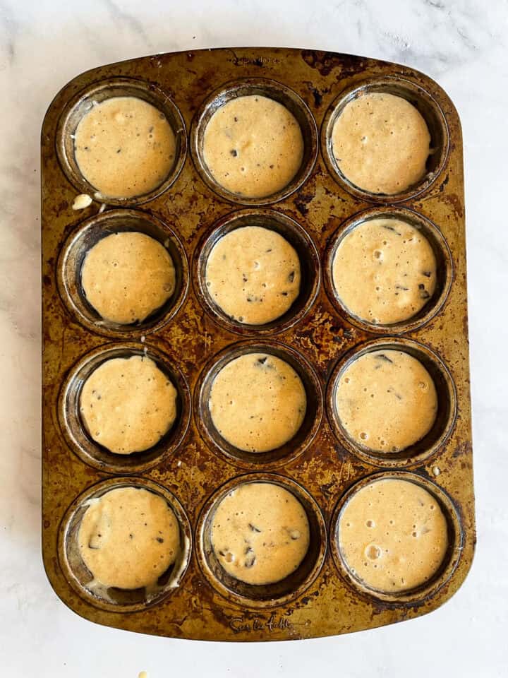 Banana chocolate chunk muffins batter in a tin.