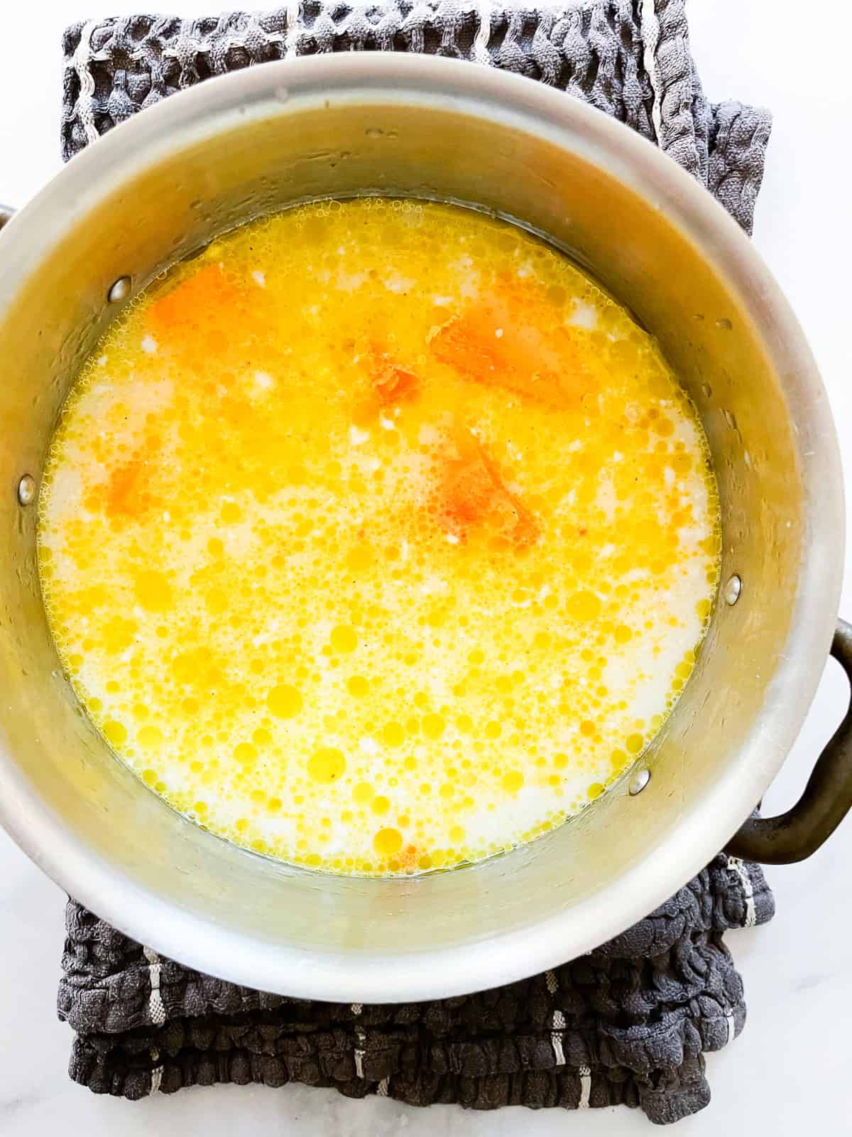 Butternut squash soup cooks in a soup pot.