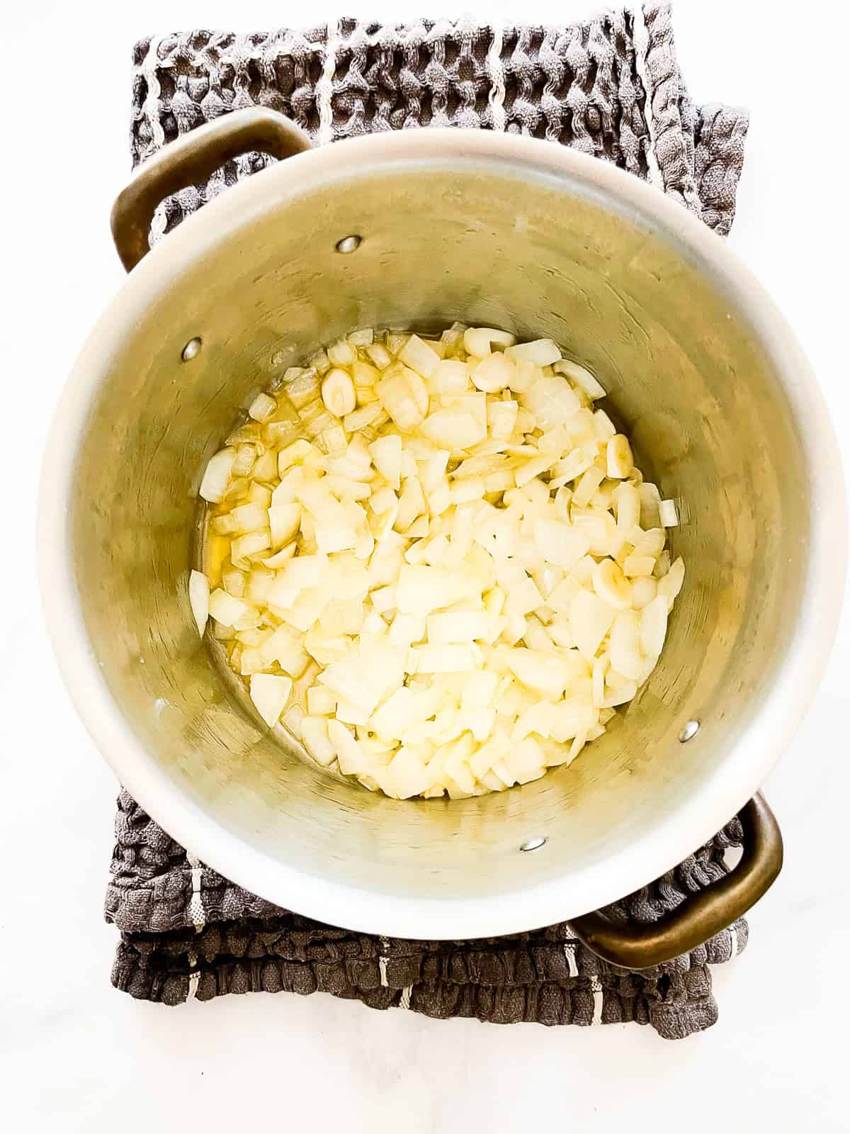 Onions and garlic cook in a pot.