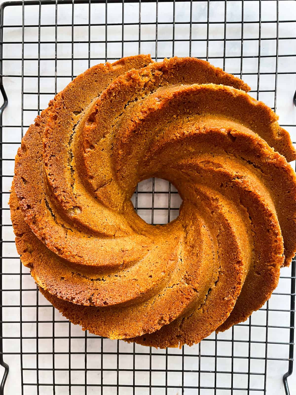 A pumpkin bundt cake cools on a rack.