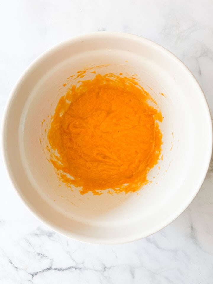 Pumpkin mixed with eggs and buttermilk in a bowl.