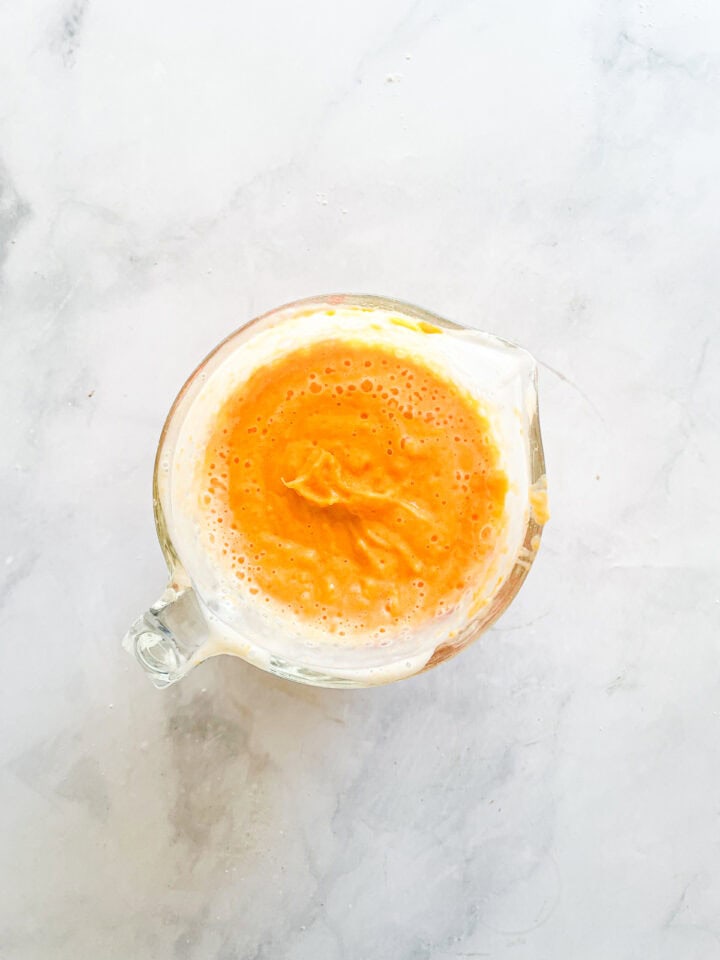 Mashed sweet potatoes mixed with buttermilk in a measuring cup.