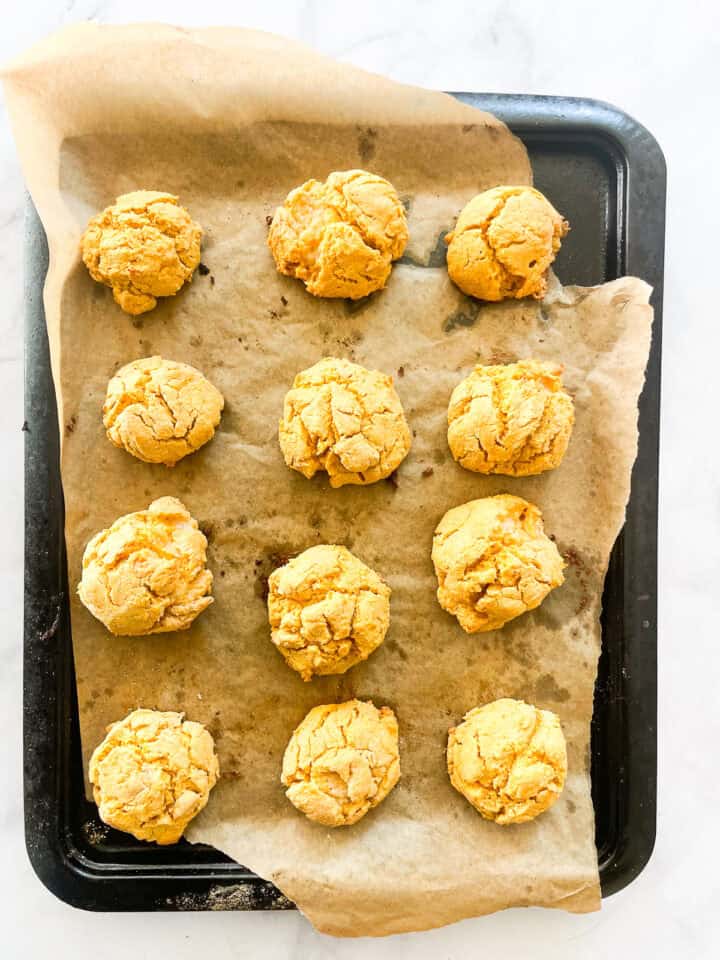 Baked sweet potato biscuits cool on a baking sheet.