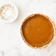 A pumpkin pie from scratch next to plates.