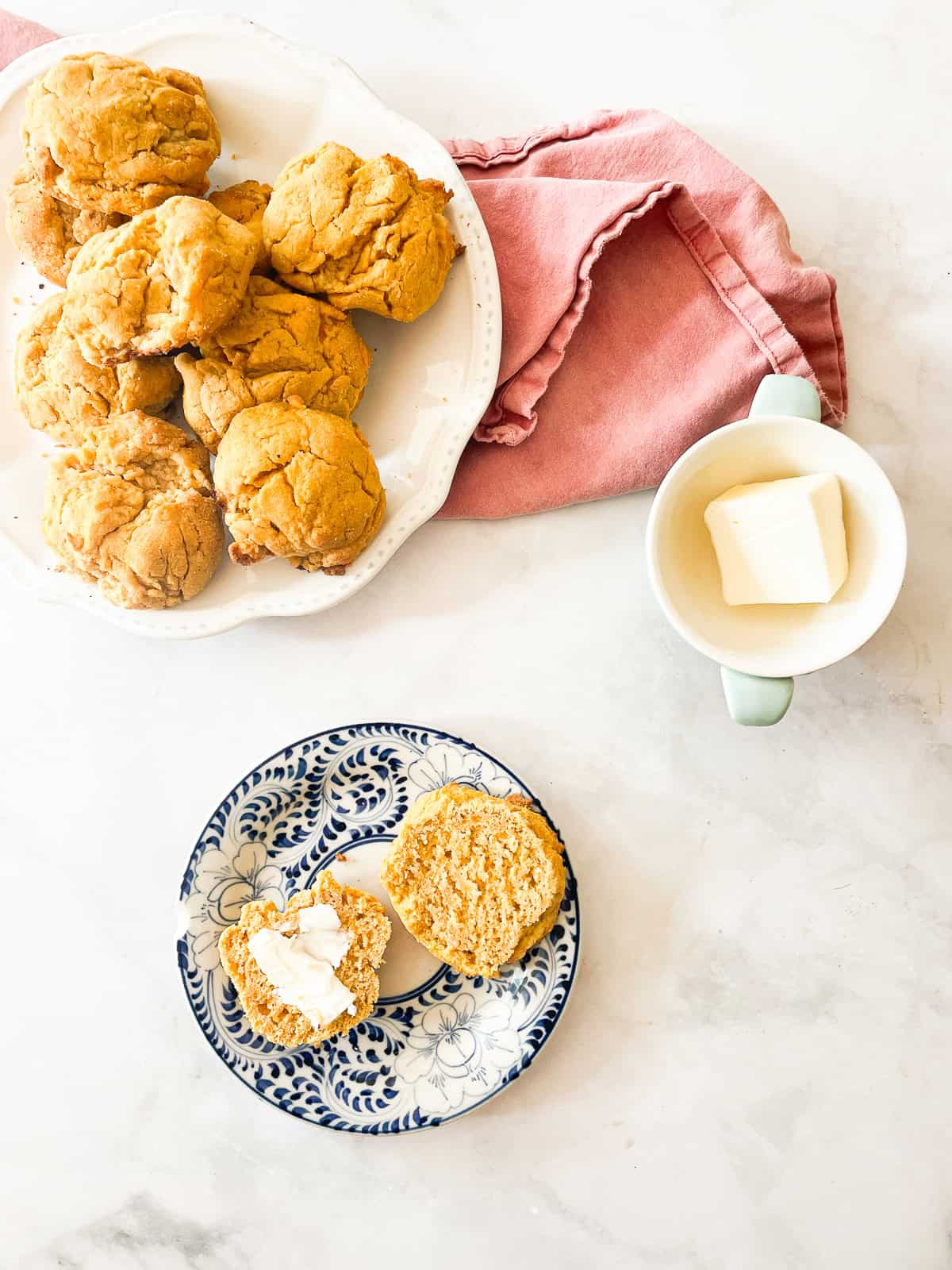 Sweet potato biscuits on plates and a dish of butter.