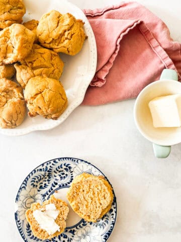 Sweet potato biscuits on plates and a dish of butter.