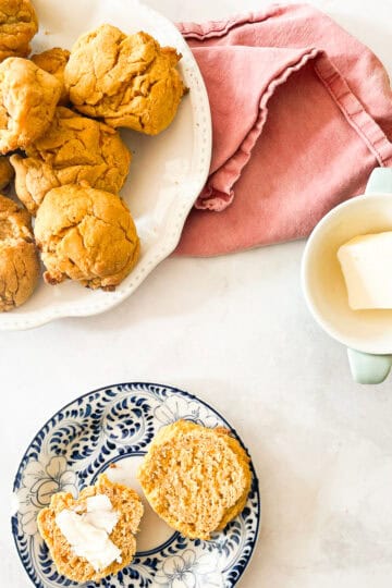Sweet potato biscuits on plates and a dish of butter.