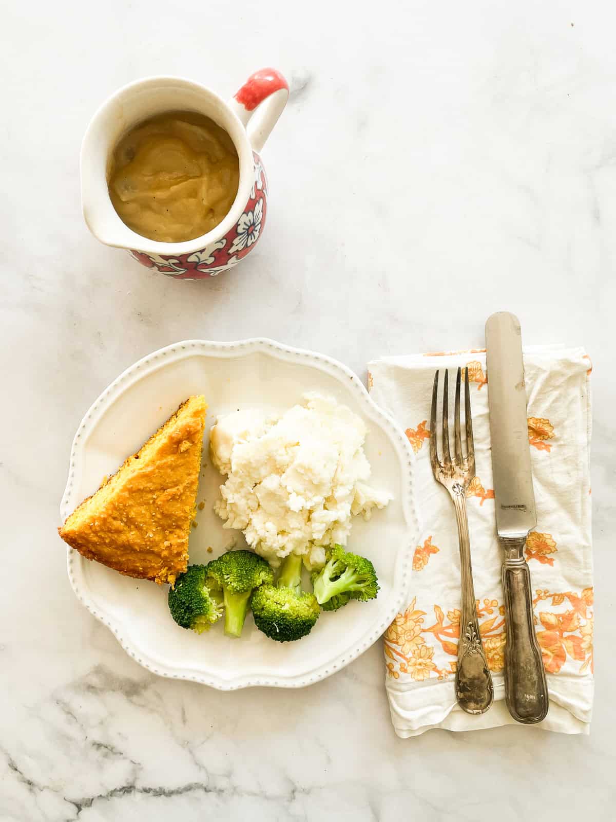 A pitcher of began gravy next to a plate of food.