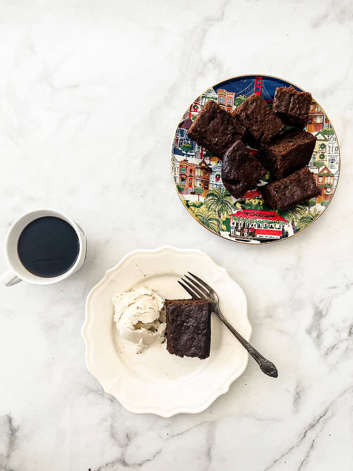 A colorful plate holds gluten free gingerbread with a cup of coffee and a plate of gingerbread nearby.