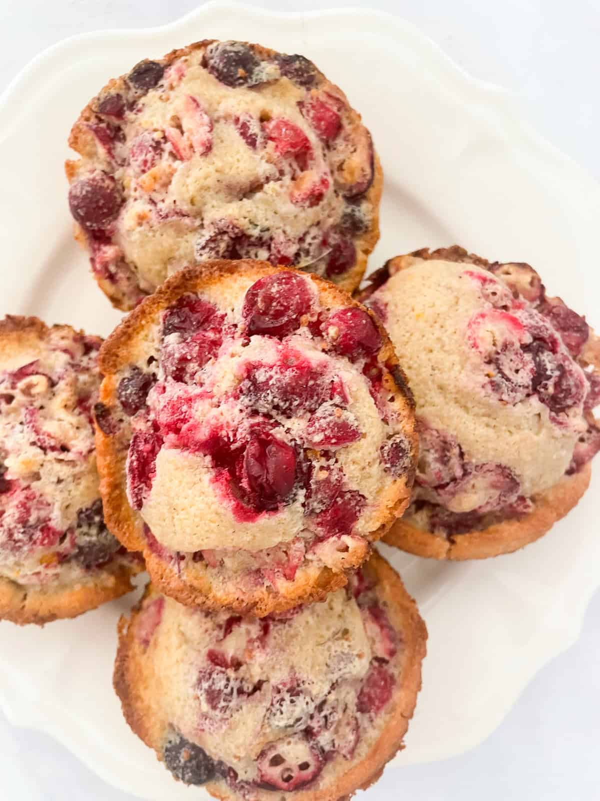 A stack of orange cranberry muffins on a plate.