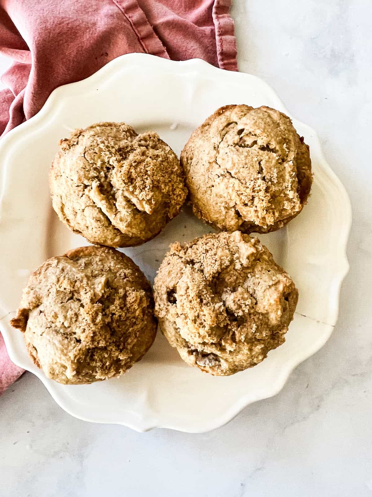 Four gluten free persimmon muffins on a plate.