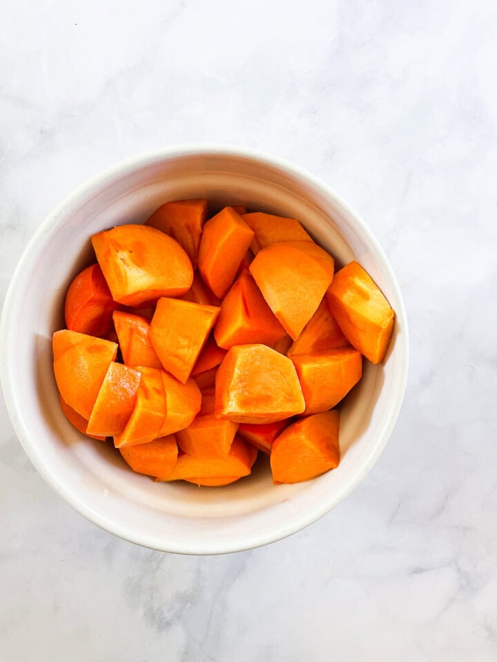 Peeled and chopped persimmon pieces in a bowl.