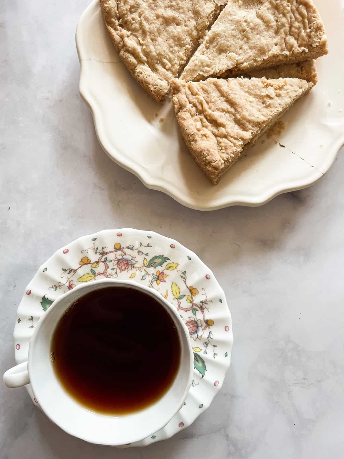 A cup of tea and sauce next to a plate of oat flour shortbread.