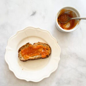 Toast with persimmon jam next to a dish of jam.