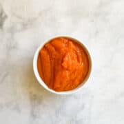 A bowl of orange persimmon puree on a counter.