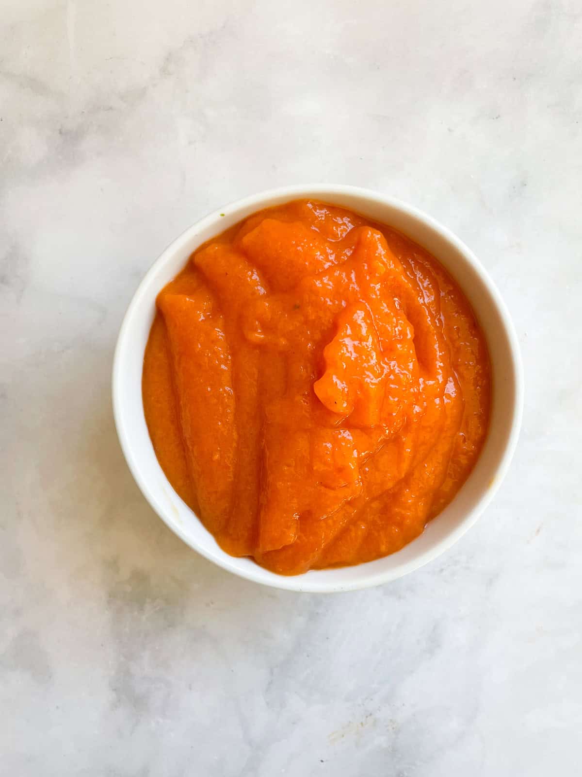 Bright orange persimmon puree in a bowl.