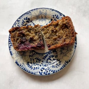 A slice of blackberry banana bread cut in half on a plate.