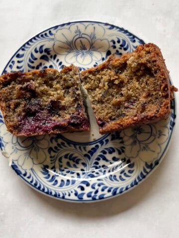 A slice of blackberry banana bread cut in half on a plate.