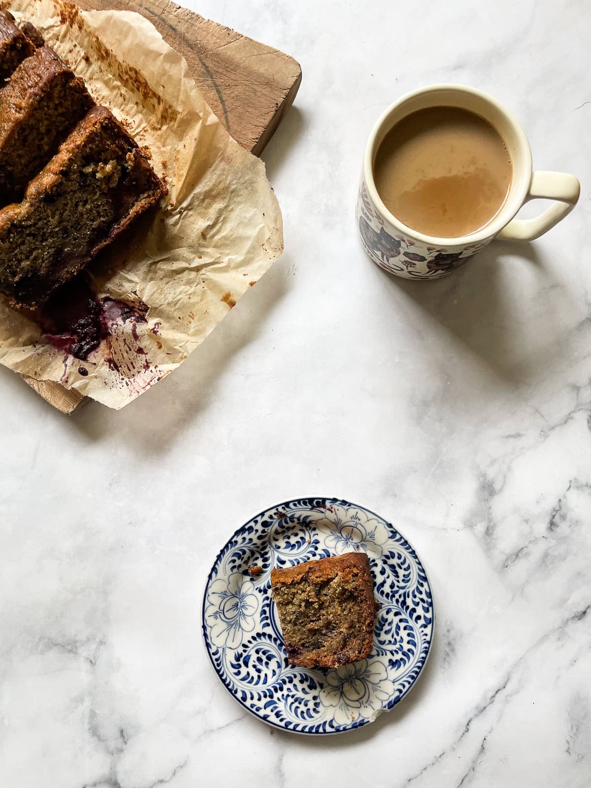 Slices of blackberry banana bread, a slice on a plate, and a cup of coffee.