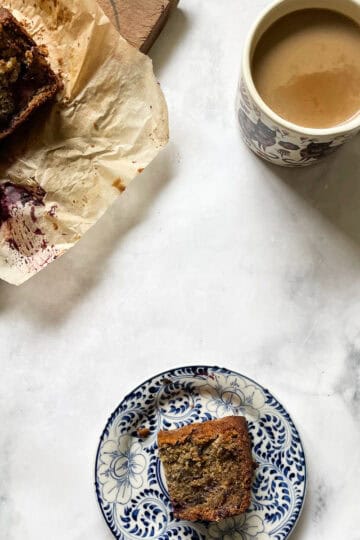 Slices of blackberry banana bread, a slice on a plate, and a cup of coffee.