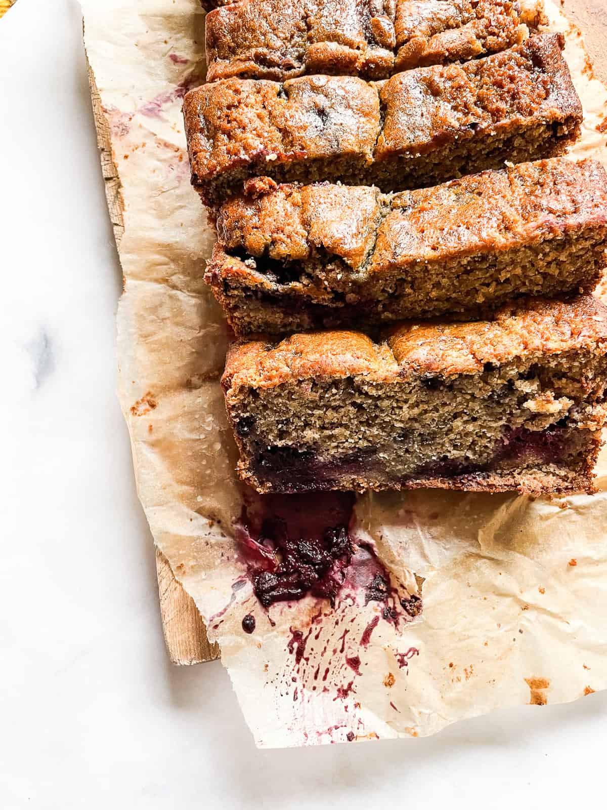 Slices of banana blackberry bread on parchment.