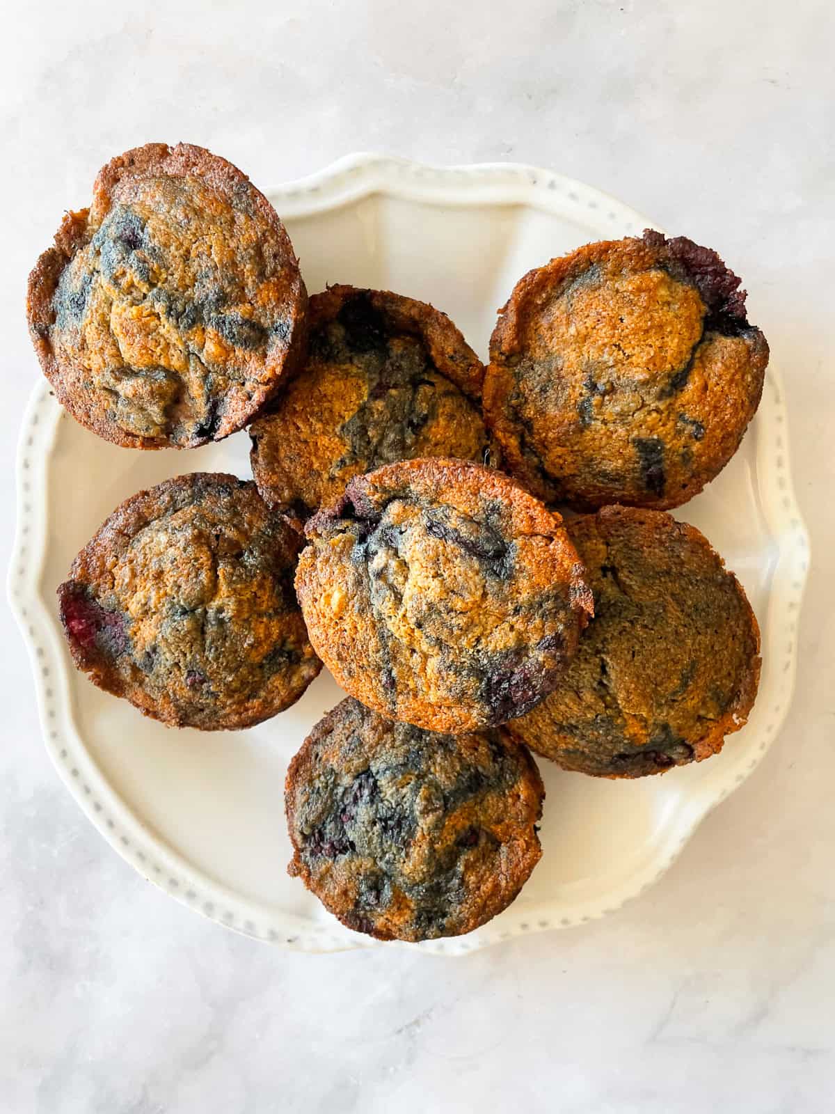 A white plate of banana blackberry muffins.