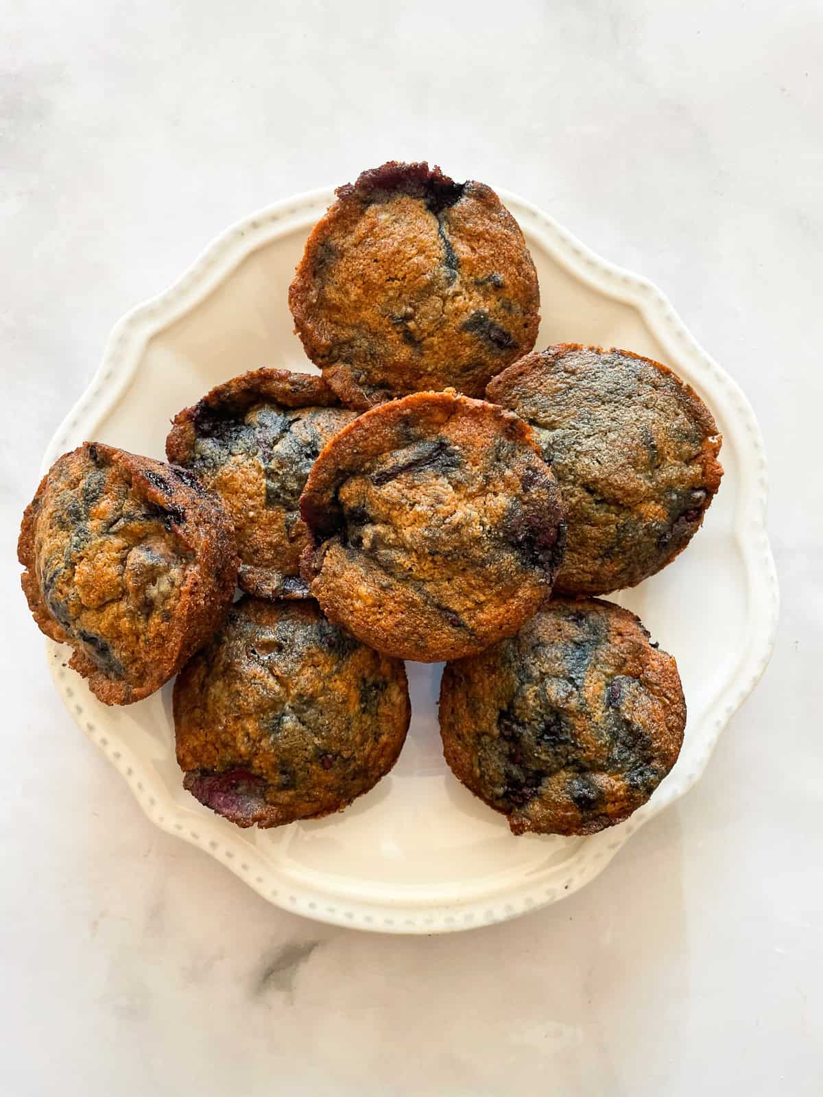 A pile of banana blackberry muffins on a plate.