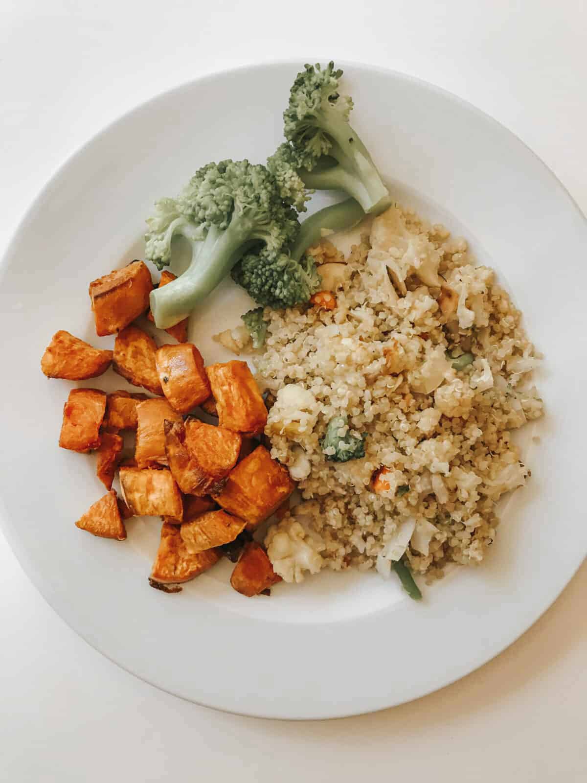 A plate of coconut quinoa, sweet potatoes, and broccoli.