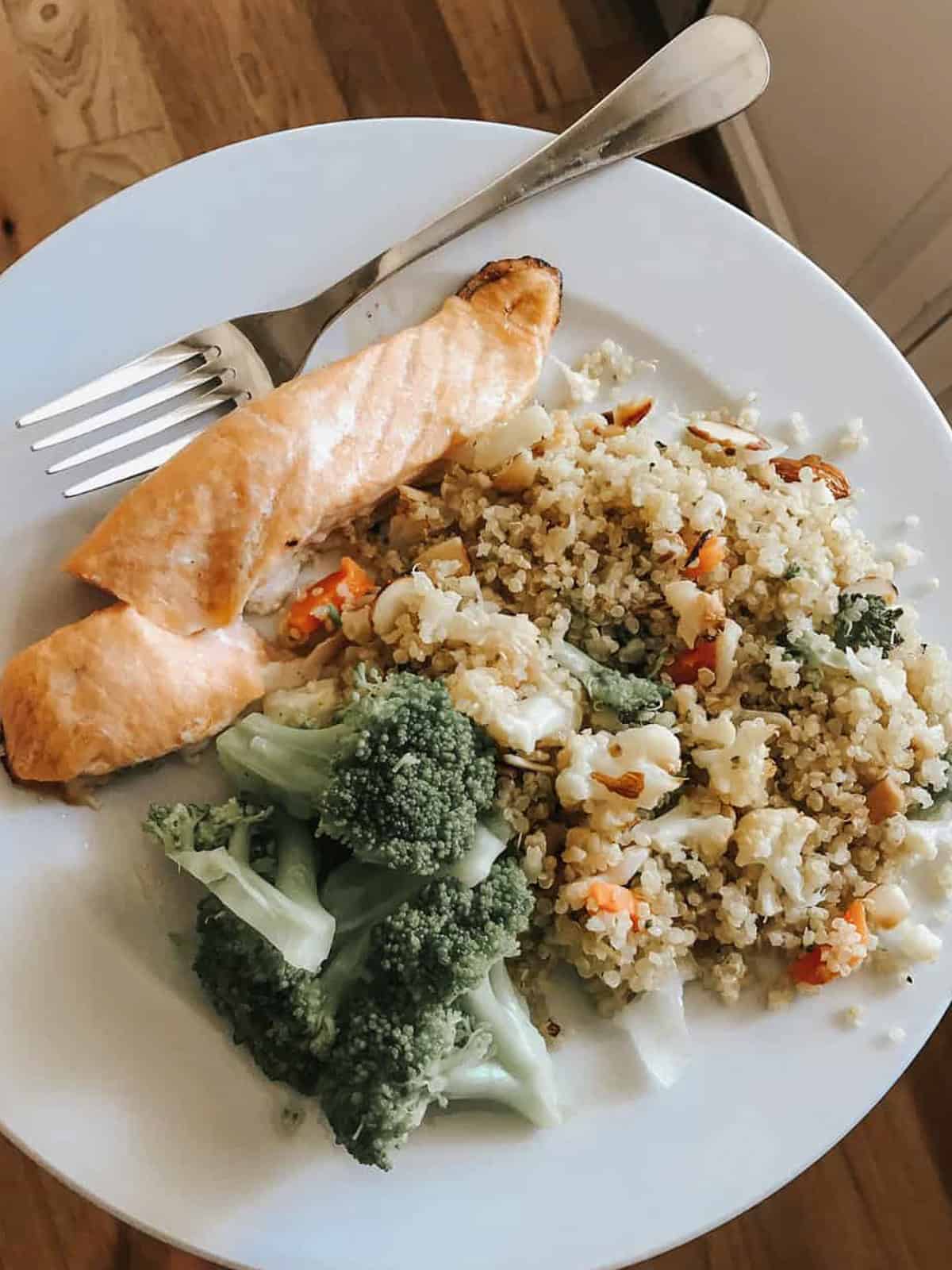 A plate of coconut quinoa with a piece of baked salmon.