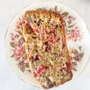 A slice of gluten free cranberry walnut bread on a plate.