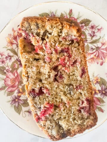 A slice of gluten free cranberry walnut bread on a plate.