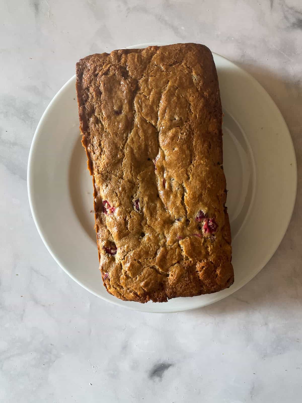 A loaf of gluten free cranberry walnut bread on a plate.