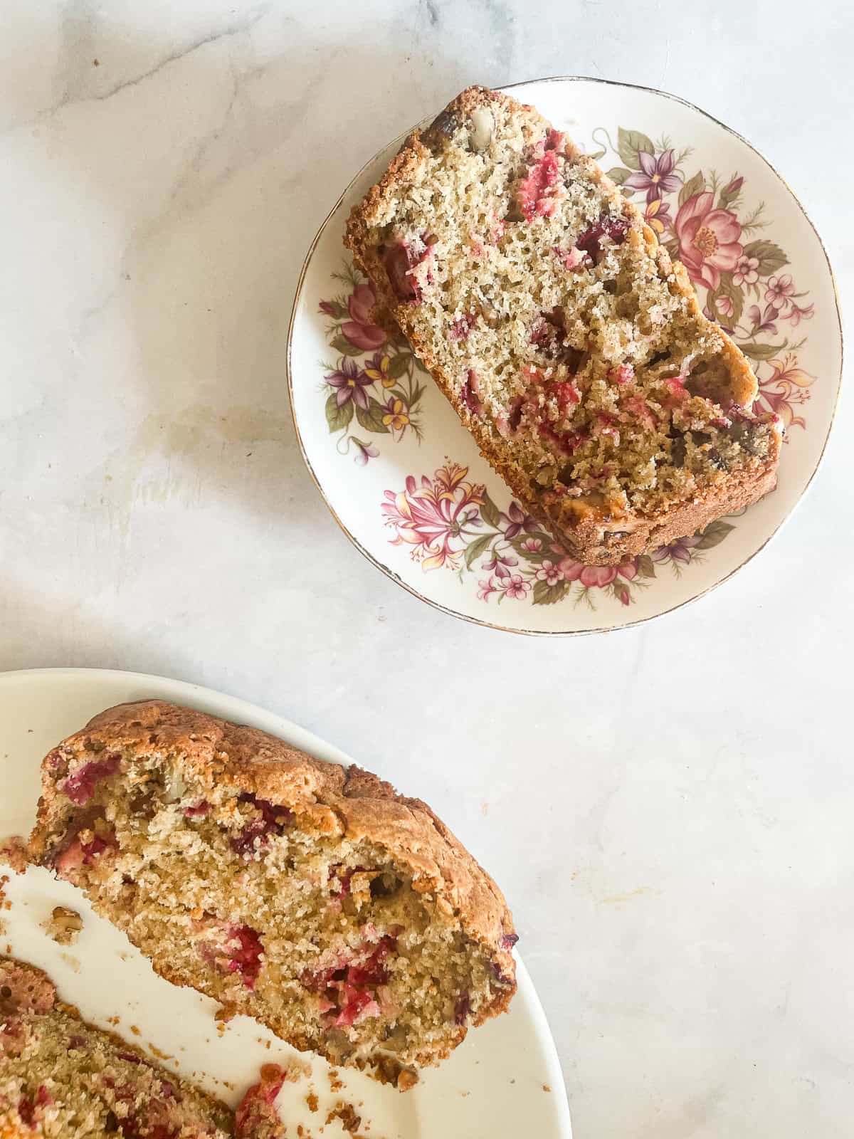 A slice of cranberry walnut bread on a plate and slices on another plate.