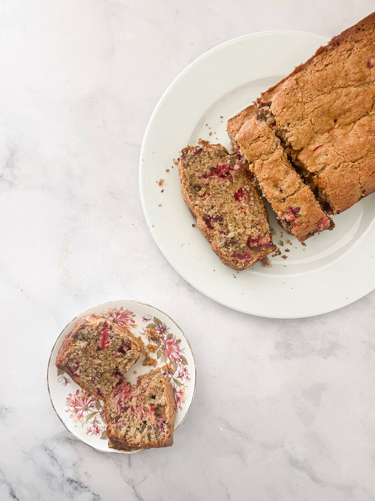 A cranberry walnut loaf sliced on a plate.