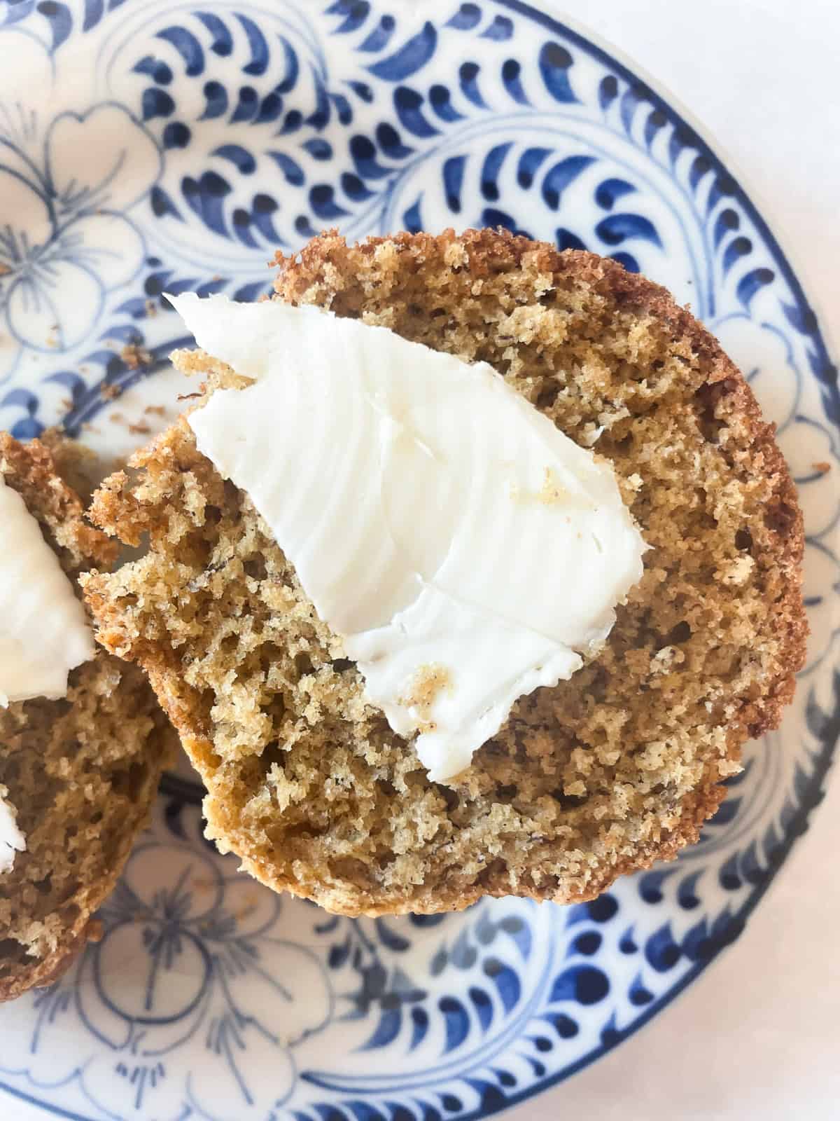 A gluten free banana bread muffin with butter on a plate.